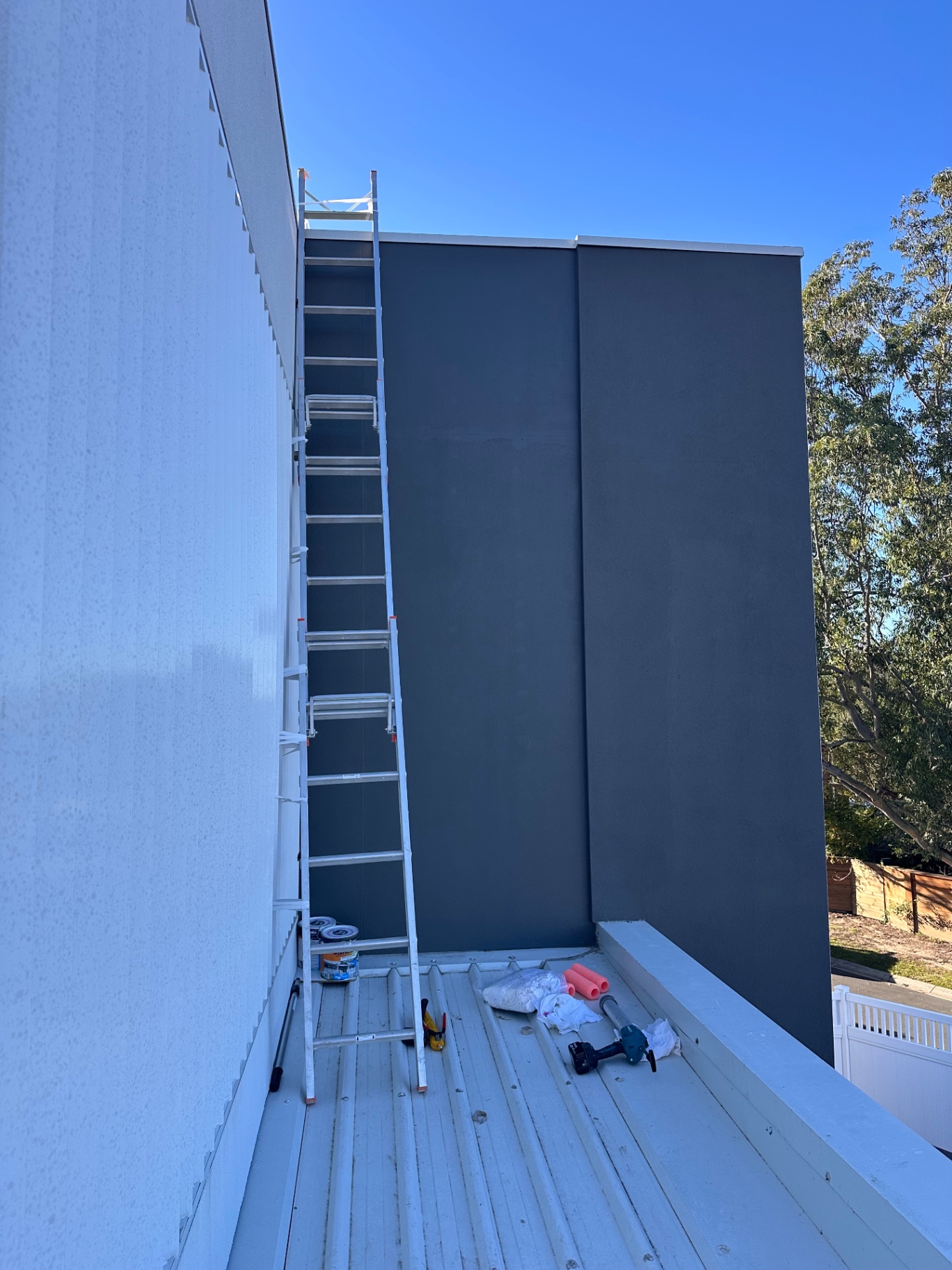 Freshly finished dark exterior wall beside a metal roof